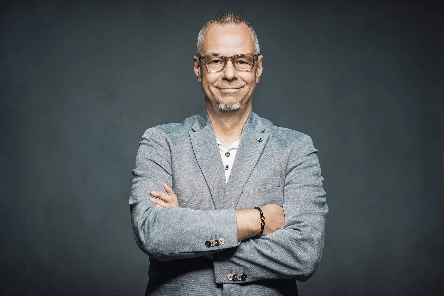 Andreas Schmitt, Fotograf und Videograf, mit verschränkten Armen vor dunklem Studiohintergrund