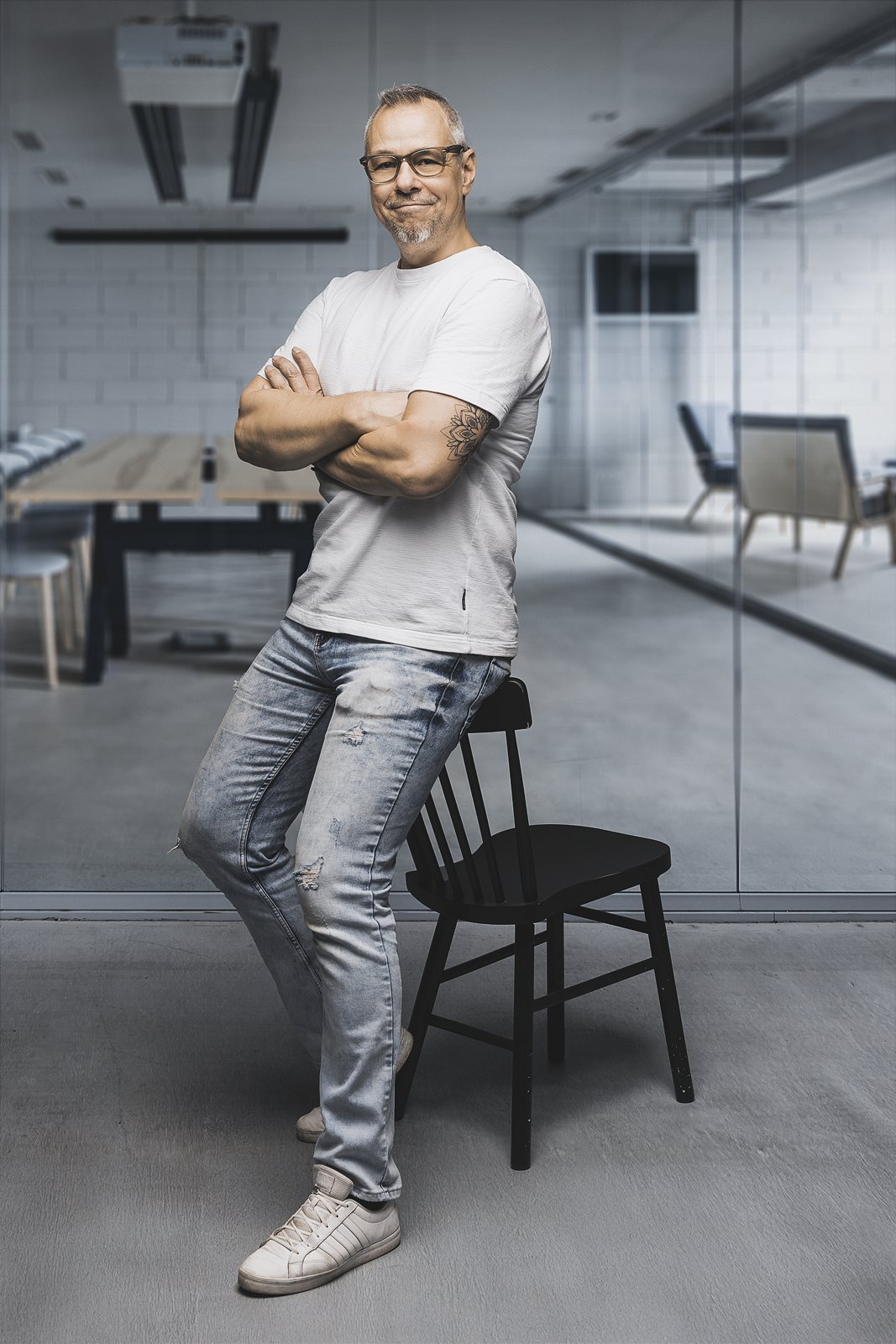 Andreas Schmitt lehnt lässig an einem Stuhl in einem hellen Büro