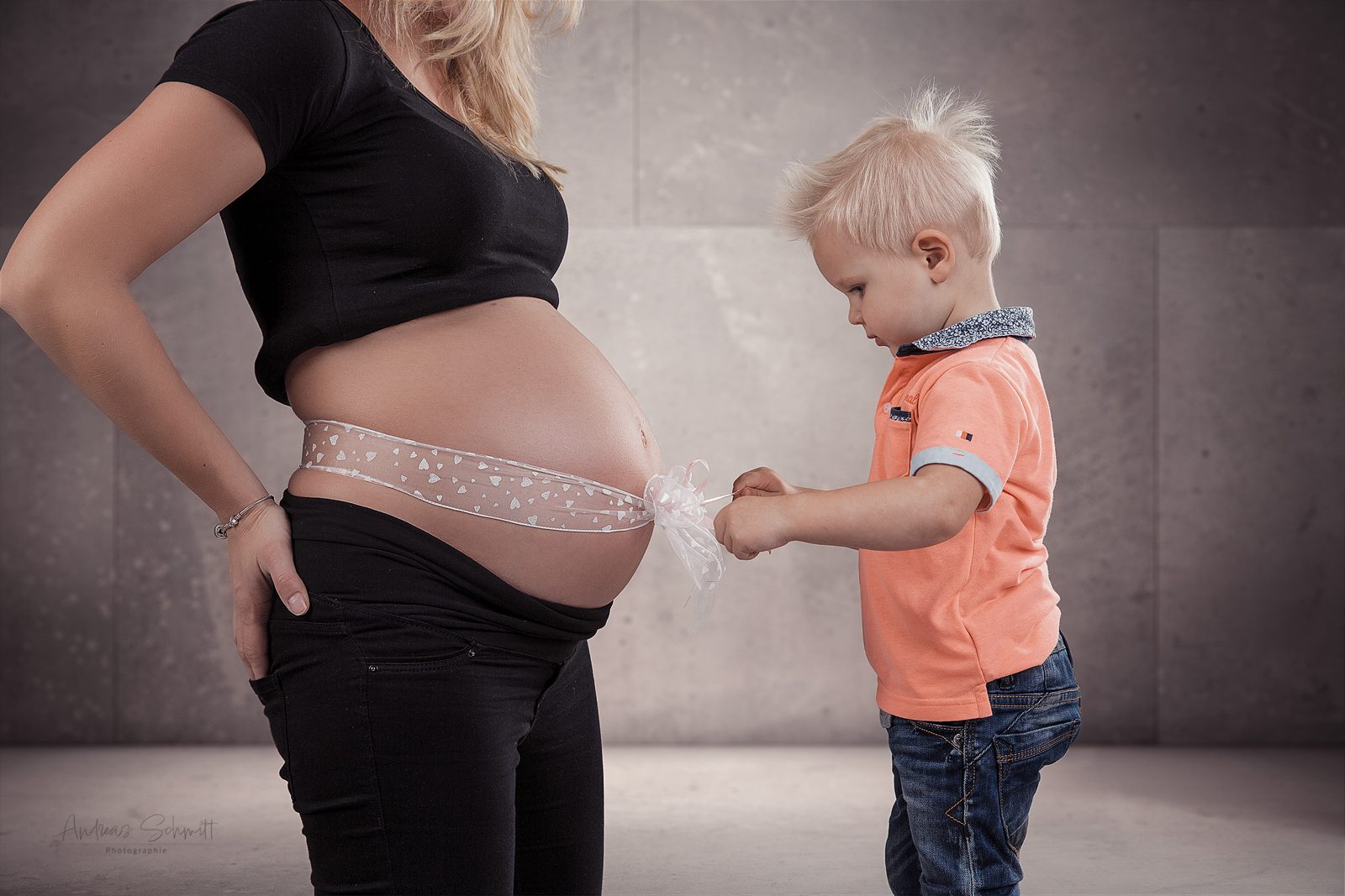 Schwangere mit kleinem Sohn, der den Babybauch betrachtet