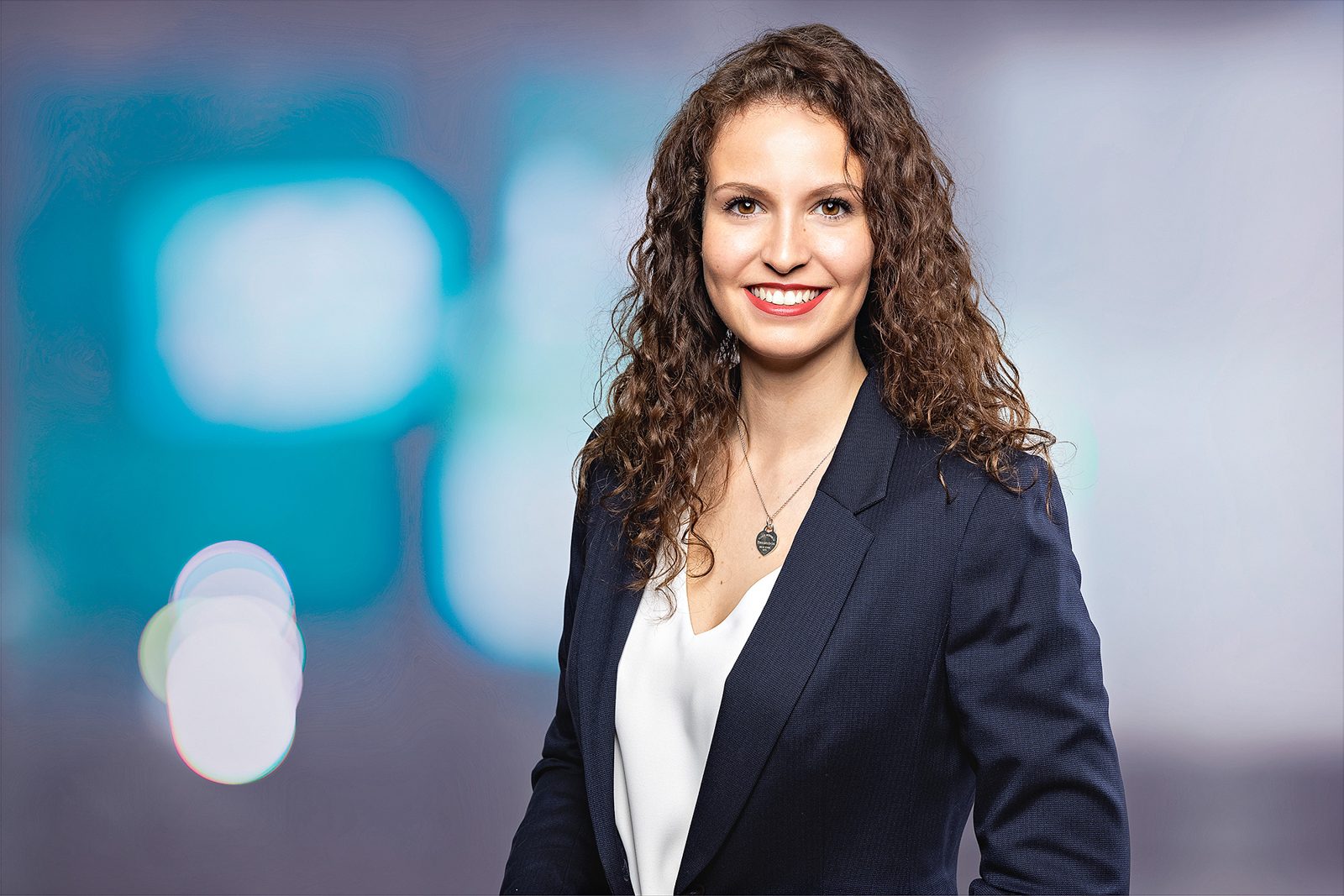Bewerbungsfoto einer Frau mit Locken vor buntem Hintergrund