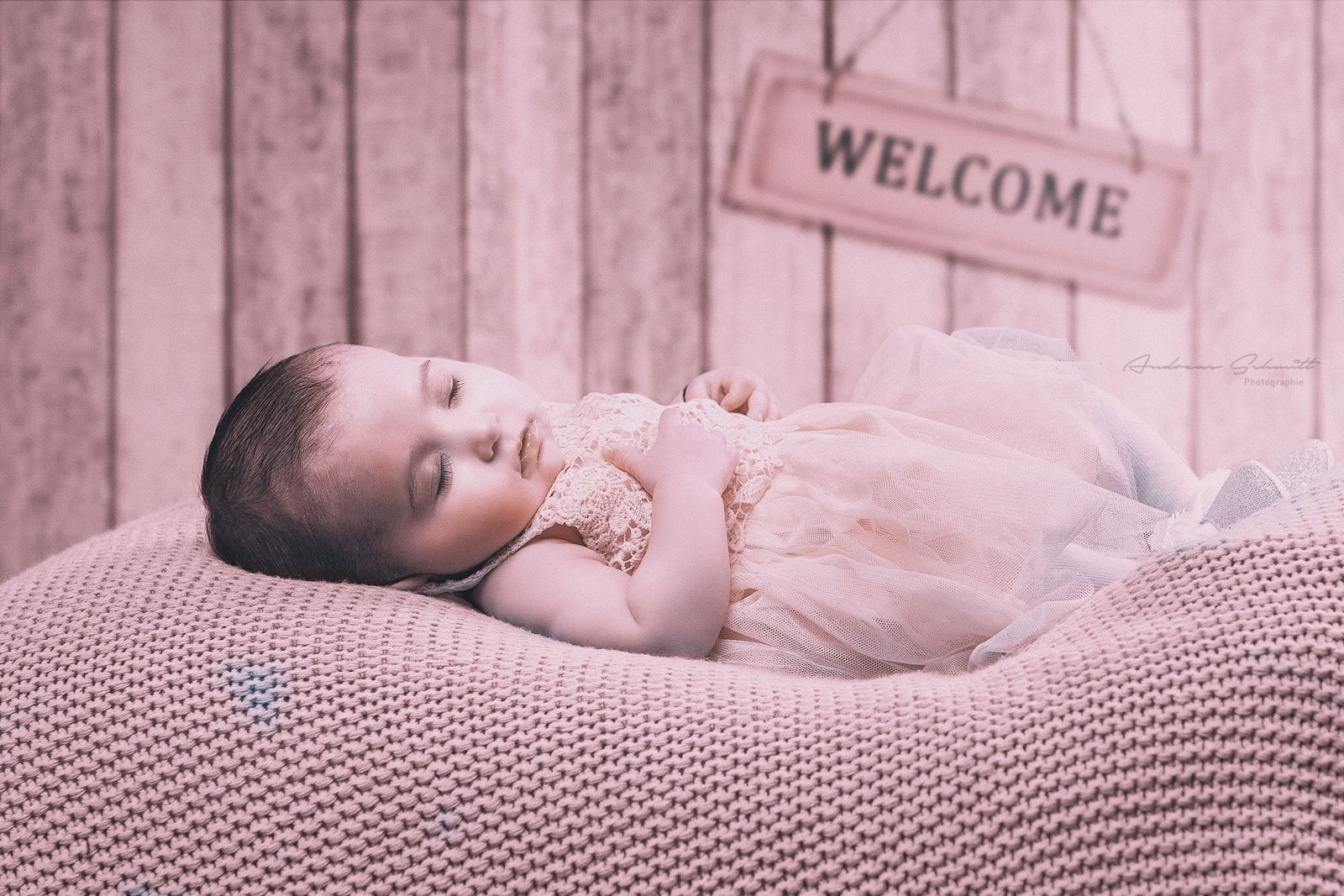 Neugeborenes schläft auf einer Decke vor einem Welcome-Schild
