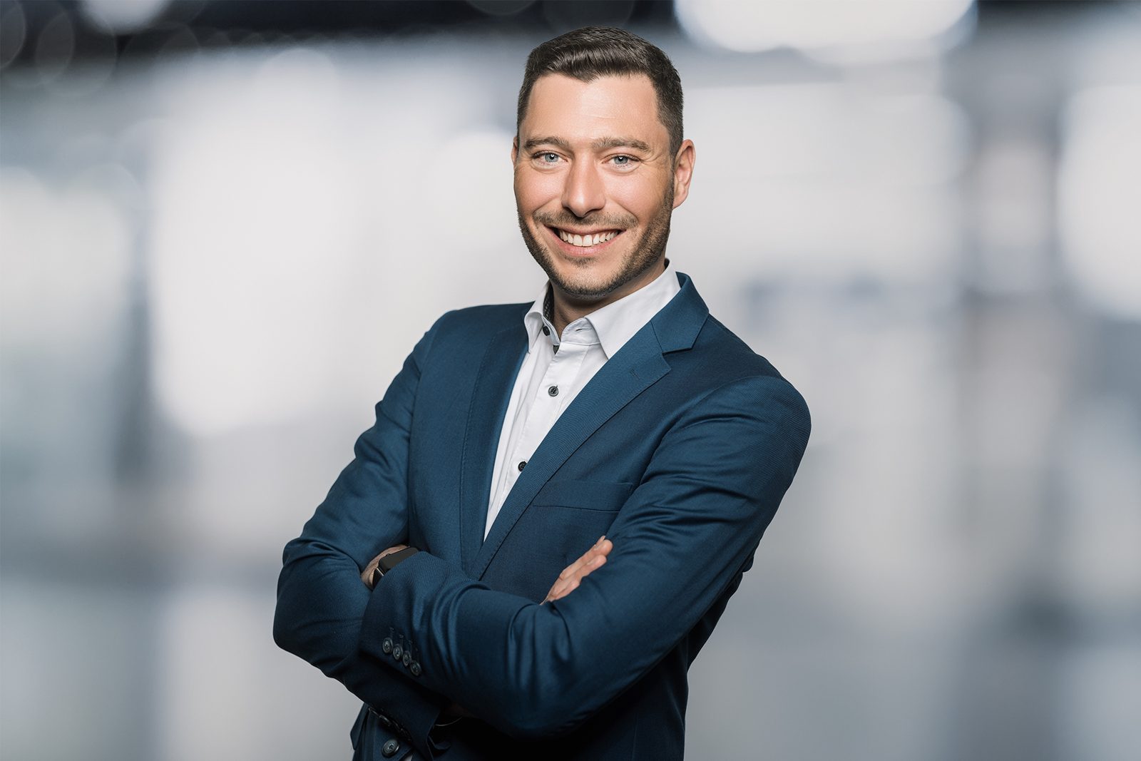Businessportrait eines Mannes im dunkelblauen Anzug mit verschränkten Armen