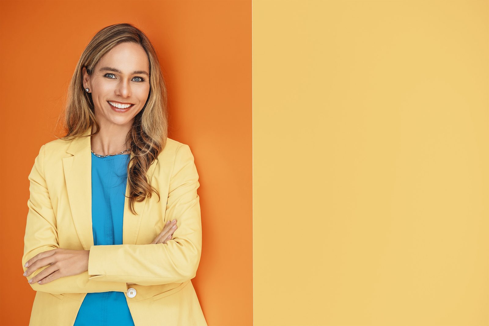 Portrait einer Frau im gelben Blazer vor orangefarbenem Hintergrund