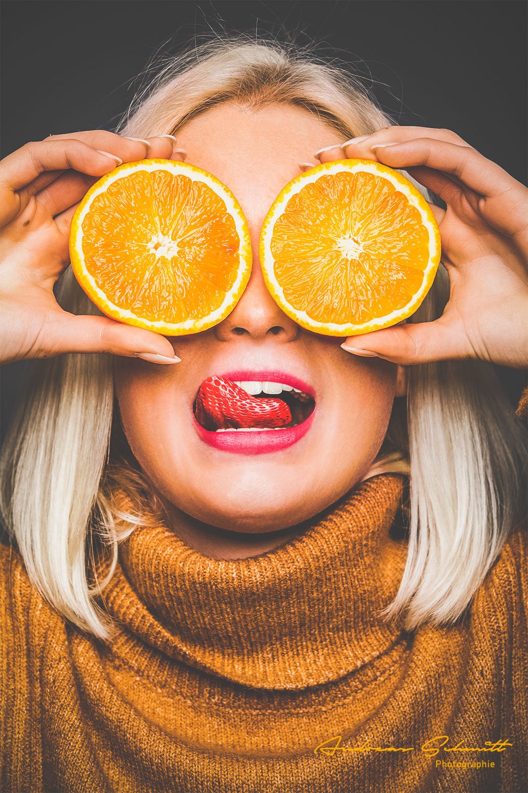 Frau hält sich zwei Orangenhälften vor die Augen