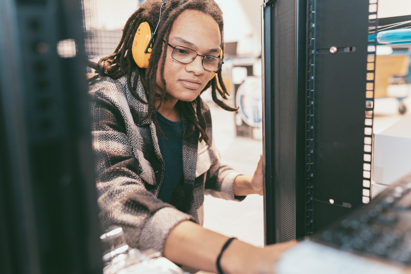 Technikerin mit Gehörschutz arbeitet im Serverraum